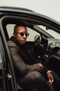 Male model Emanuel Jones, Jr. sitting and posing in a Bentley Bentayga.